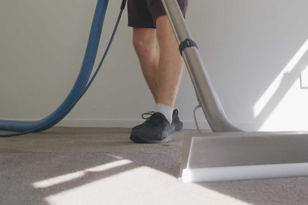 Close-up of a truck-mounted carpet cleaning wand extracting hot water from carpet