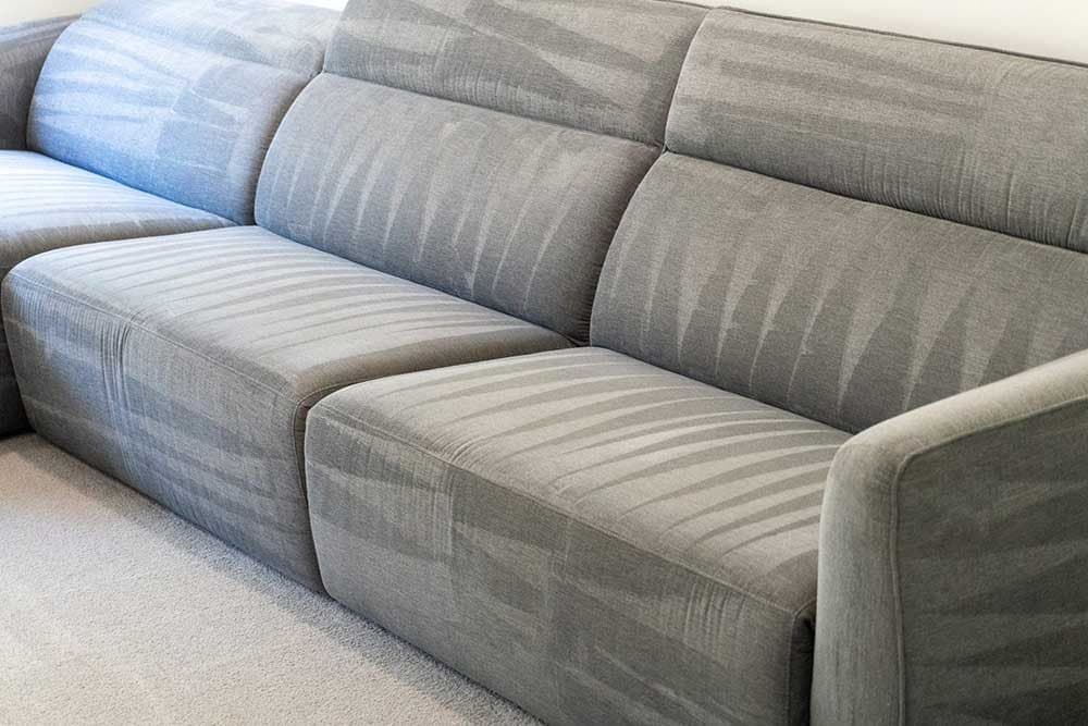 Grey fabric lounge with fresh steam-cleaning lines after a professional couch clean